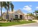 Tan colored house with lush landscaping and palm trees at 1010 Grouse Way, Venice, FL 34285