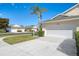 Exterior view of a villa with a white garage door, palm trees, and a paved driveway at 1102 Auburn Cove Cir, Venice, FL 34292