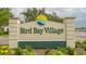 Bird Bay Village community sign with manicured landscaping and bright yellow flowers at 1106 Bird Bay Way # 316, Venice, FL 34285