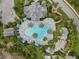 Overhead view of pool area with lush landscaping, lounge chairs, poolside structures, and roads at 11140 Hogan Cir, Englewood, FL 34223