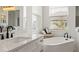 Bright bathroom featuring dual vanity and soaking tub under the window with plantation shutters at 11140 Hogan Cir, Englewood, FL 34223
