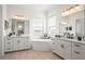 A luxurious bathroom with dual sinks, free-standing tub, wood-look tile, and bright lighting at 11140 Hogan Cir, Englewood, FL 34223