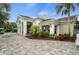 Elegant exterior featuring a paved patio, beautiful landscaping, and architectural columns at 11140 Hogan Cir, Englewood, FL 34223