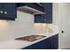 Close-up of a kitchen featuring navy blue cabinets and a white backsplash and countertop with cooktop at 11140 Hogan Cir, Englewood, FL 34223