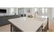 Close up of modern kitchen island with white counter tops, a farmhouse sink, and view into the living room at 11140 Hogan Cir, Englewood, FL 34223