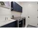 A modern laundry room with washer, dryer, navy cabinets and white sink at 11140 Hogan Cir, Englewood, FL 34223