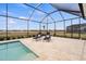 Inviting screened-in pool with lounge chairs and view of the surrounding landscape at 11140 Hogan Cir, Englewood, FL 34223