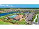 An aerial view shows a community pool, clubhouse, tennis courts, and parking with mature trees, all near a scenic lake at 18861 Bianchi St, Venice, FL 34293