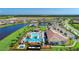 Aerial view of a community pool and clubhouse with mature trees, tennis courts, parking, and waterfront views at 18861 Bianchi St, Venice, FL 34293