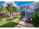 Pathway leads to a screen enclosed lanai with view of lush backyard landscaping at 18861 Bianchi St, Venice, FL 34293