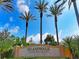 Community entrance sign with lush palm trees against a blue sky, offering a tropical and welcoming feel at 18861 Bianchi St, Venice, FL 34293