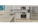 Modern kitchen featuring granite counters, stainless steel appliances, tile backsplash, and white cabinetry at 18861 Bianchi St, Venice, FL 34293