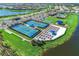 An aerial view of community pickleball courts with sunshades for players, lounge seating, and nearby lake at 18861 Bianchi St, Venice, FL 34293