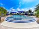 A resort-style pool features shallow wading area with fountains and blue umbrellas, surrounded by palm trees and lounge chairs at 18861 Bianchi St, Venice, FL 34293
