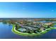 Spacious aerial shot of community tennis courts, lake, pool, and lush landscaping with community homes in the background at 18861 Bianchi St, Venice, FL 34293