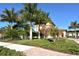 Attractive community building surrounded by lush green landscaping, including palm trees and manicured shrubs at 20590 Granlago Dr, Venice, FL 34293