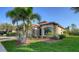 Landscaped front yard with mature palm trees and green grass surrounding the home's exterior at 20590 Granlago Dr, Venice, FL 34293