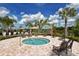 Relaxing community spa with lounge chairs under a blue sky with fluffy white clouds and palm trees at 20590 Granlago Dr, Venice, FL 34293