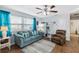 Bright living room with a comfortable blue sofa, ceiling fan, and wood-look flooring at 21379 Gladis Ave, Port Charlotte, FL 33952