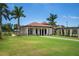 Community clubhouse with a lawn, palm trees, and walkway at 23499 Awabuki Dr # 102, Venice, FL 34293