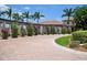 Grand entrance with brick pavers, pergola, and lush landscaping at 23499 Awabuki Dr # 102, Venice, FL 34293