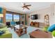 Open living area with green sofas and a large TV at 23499 Awabuki Dr # 102, Venice, FL 34293