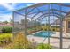 A serene view of the screened pool and patio from the yard, offering a private outdoor retreat at 357 Marsh Creek Rd, Venice, FL 34292
