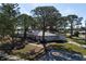Single-story home nestled among mature trees, showcasing a tile roof and driveway at 407 Degas Dr, Nokomis, FL 34275