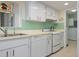 White kitchen with green backsplash and access to laundry room at 407 Degas Dr, Nokomis, FL 34275