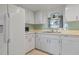 White kitchen cabinets, green tile backsplash, and stainless steel appliances at 407 Degas Dr, Nokomis, FL 34275