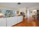 Living room with white sectional sofa, sunroom, wood floors, and mid century modern decor at 407 Degas Dr, Nokomis, FL 34275
