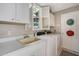 Bright laundry room with neutral colors, white cabinets, folding counter, laundry sink, and plantation shutters at 522 Fallbrook Dr, Venice, FL 34292