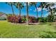 Landscaped backyard featuring palm trees, red flowering bushes and green lawn at 523 Park Estates Sq, Venice, FL 34293