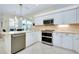 Modern kitchen with stainless steel appliances, white cabinets, and a breakfast bar at 523 Park Estates Sq, Venice, FL 34293