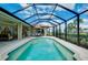 Inviting in-ground pool with screened enclosure, patio furniture, and lush landscaping at 523 Park Estates Sq, Venice, FL 34293