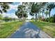 Paved walking path along a waterfront, surrounded by lush greenery and shady trees at 523 Park Estates Sq, Venice, FL 34293