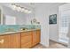 Elegant bathroom with dual sinks, light wood cabinets, and a teal tile accent at 8230 Harborside Cir, Englewood, FL 34224