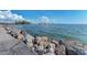 Rocky shoreline with calm water and distant buildings at 927 Capri Isles Blvd # 7, Venice, FL 34292