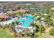 Aerial view of a community pool featuring tropical landscaping, a clubhouse, and nearby tennis courts at 10117 Colubrina Dr, Venice, FL 34293