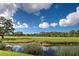 Scenic view of golf course, lake, and trees under a blue sky at 1041 Capri Isles Blvd # 119, Venice, FL 34292