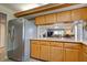 Kitchen with wooden cabinets and stainless steel refrigerator looking into the living and dining area at 1041 Capri Isles Blvd # 119, Venice, FL 34292