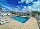 Community pool with lounge chairs and a brick patio under a blue sky with fluffy white clouds at 1041 Capri Isles Blvd # 119, Venice, FL 34292