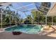 Enclosed pool area with a spa, lush landscaping, and clear blue water at 1093 Laurel Woods Dr, Nokomis, FL 34275