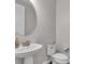 Neutral powder room featuring a pedestal sink, round mirror, and toilet at 11903 Alessandro Ln, Venice, FL 34293