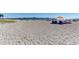 Wide sandy beach with a fishing pier in the distance. People lounge under umbrellas along the shoreline at 11903 Alessandro Ln, Venice, FL 34293