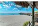 Beach and pier view framed by a thatched roof and vegetation, offering a tropical ambiance at 11903 Alessandro Ln, Venice, FL 34293