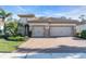 Charming home with a two-car garage, brick driveway, manicured lawn, and lush landscaping at 11903 Alessandro Ln, Venice, FL 34293