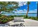 Scenic lake view featuring a tranquil bench, lush landscaping, and a pier under a bright blue sky at 11903 Alessandro Ln, Venice, FL 34293