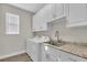 Well-equipped laundry room with built-in cabinets, sink, and modern washer and dryer at 11903 Alessandro Ln, Venice, FL 34293