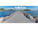 Scenic view of a pier extending into the ocean, framed by a rocky shoreline and clear blue waters at 11903 Alessandro Ln, Venice, FL 34293